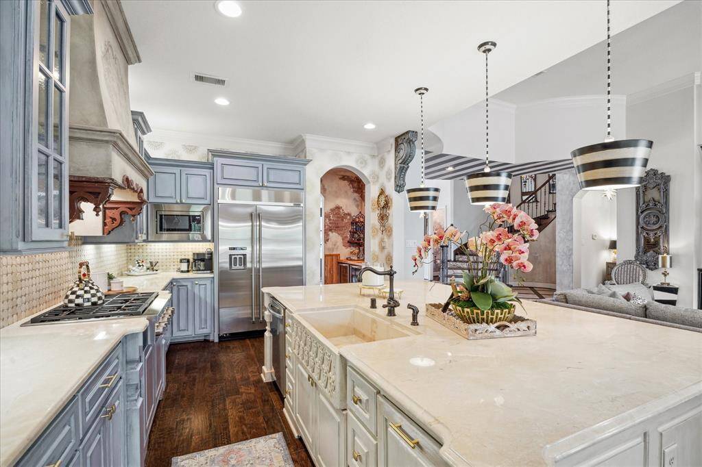 An enormous, custom, hand-carved travertine sinks finds its home centered in the expansive island. Anchoring the kitchen, the island houses the dishwasher and convenient trash receptacle and provides seating and storage.