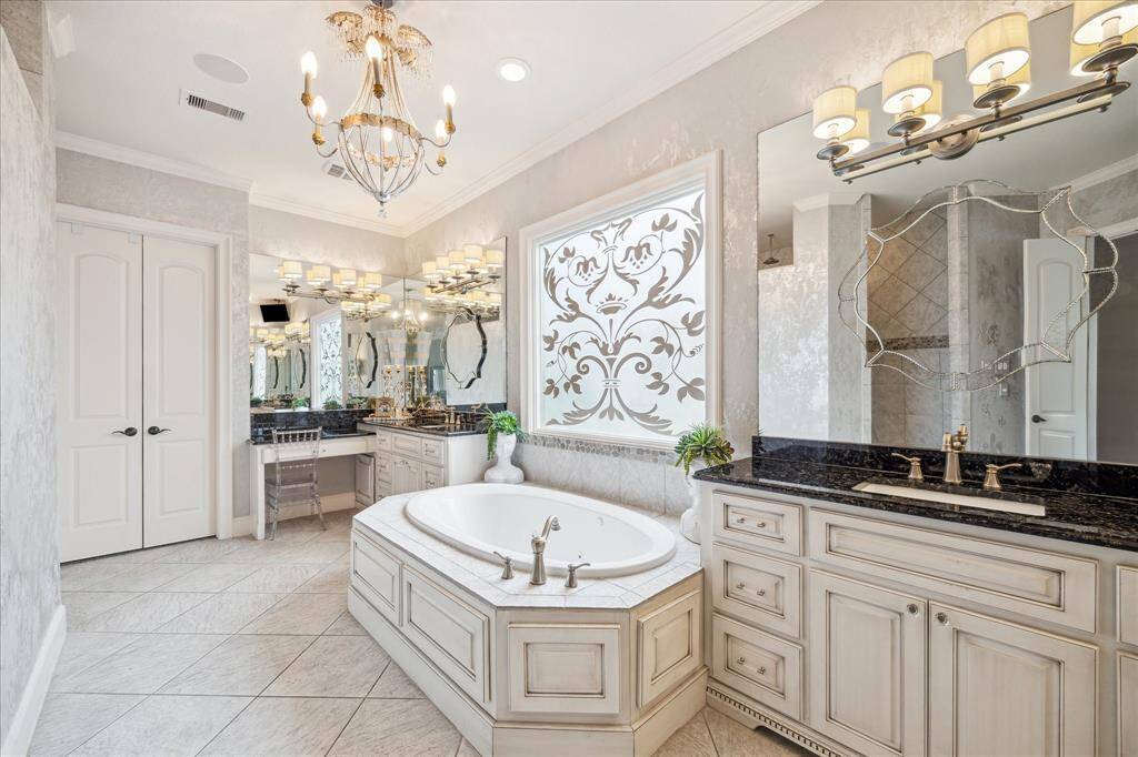 Expansive vanities with classic finishes and elegant wallpaper make daily routines feel luxurious in this primary bath. The large custom glass window provides natural light while maintaining privacy.