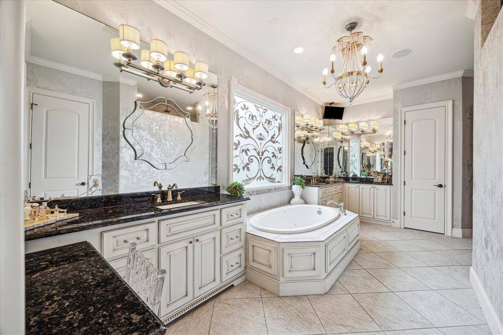The brass and crystal chandelier bestow a glamourous feeling to this primary retreat.