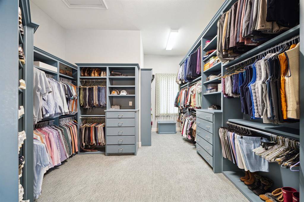 The French doors lead to the oversized primary closet finished in a sophisticated palette. The space will accommodate your entire wardrobe and features a window allowing in natural light.