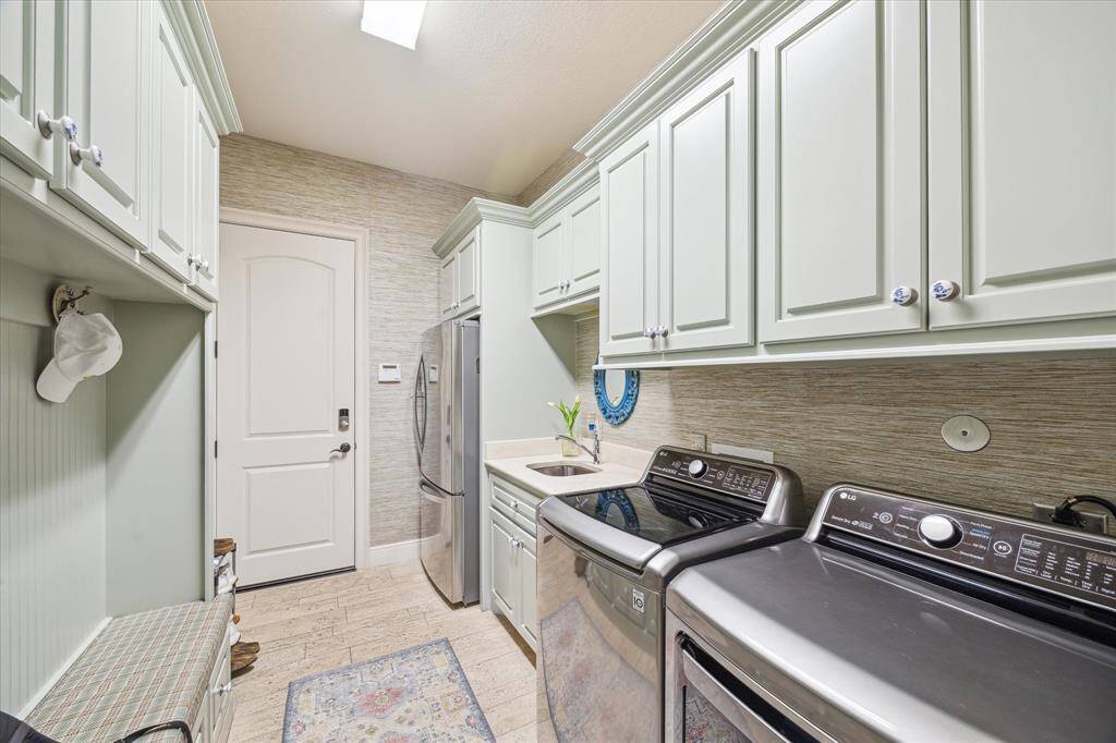 The coveted mud & utility room provides convenient access directly from the garage. Significant storage cabinetry and designated spaces for jackets, hats, shoes and purses keep clutter contained and easily grabbed when running out the door. A second refrigerator and utility sink offer additional convenience. The oversized garage boasts epoxy flooring.