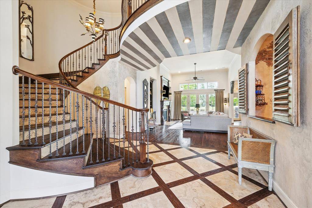 The sweeping wood staircase with detailed wrought iron spindles creates a dramatic focal point in the entry. Meticulous attention to detail includes the striped faux paint on the ceiling of the second floor landing as well as the patterned wood and travertine flooring of the formal entry.