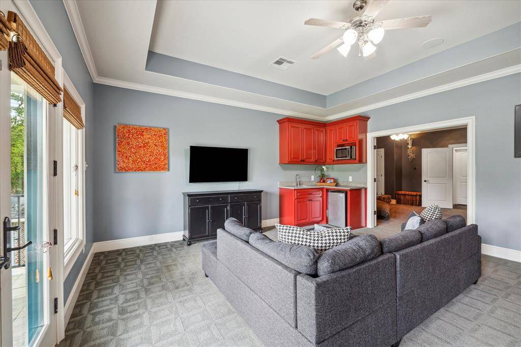 The game room is secluded in the rear corner of the house which prevents game-time celebrations from disturbing those downstairs. It features a wet bar kitchenette complete with beverage refrigerator and microwave for popping popcorn within bold cabinetry stylishly housing dishes and snacks.