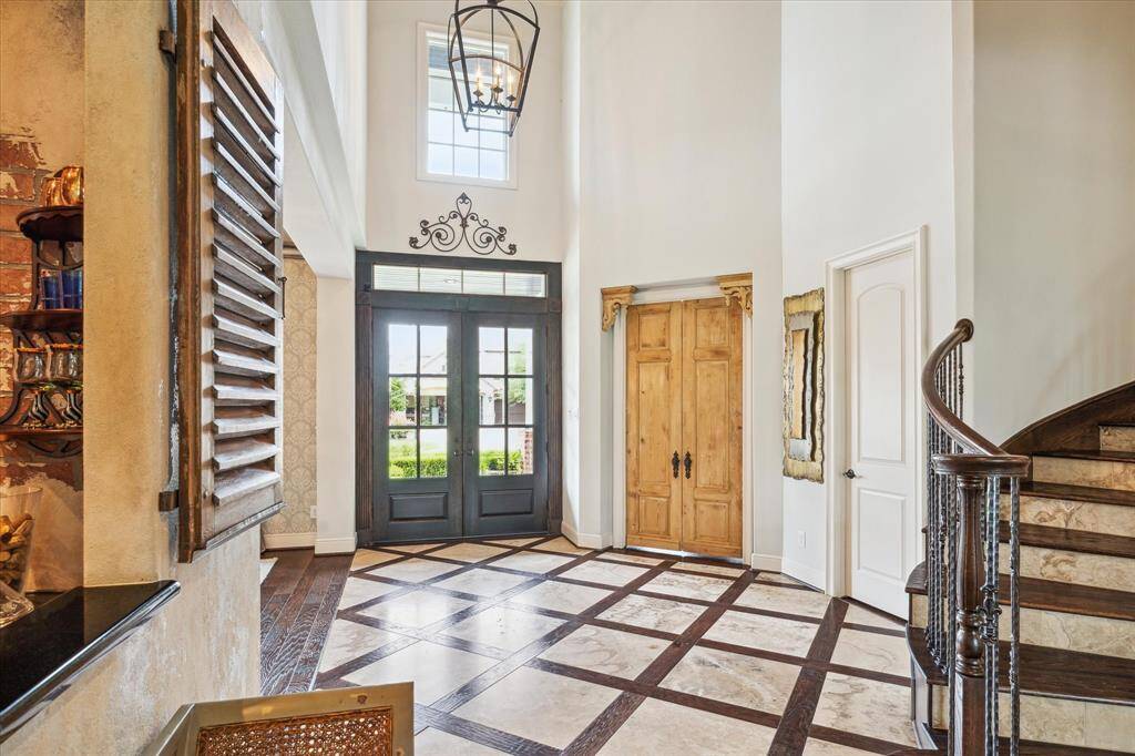 The grand two story entry features a double glass French front door system with accompanying transom to greet guests and bathe the foyer in natural light. Step into the study through reclaimed antique wooden French doors with original hardware accented at the head with antique corbels reclaimed from a New Orleans home.