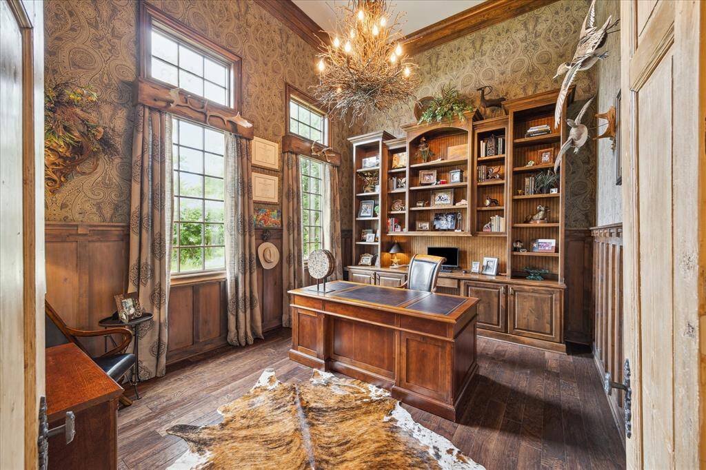This sophisticated, private study is located just off the formal entry. Warmly stained wood floors, millwork, molding and bookcases complemented by walls clad in rich, understated wallpaper create a moody milieu from which to work. A custom hand-made chandelier descends from the soaring two story ceiling illuminating the library.