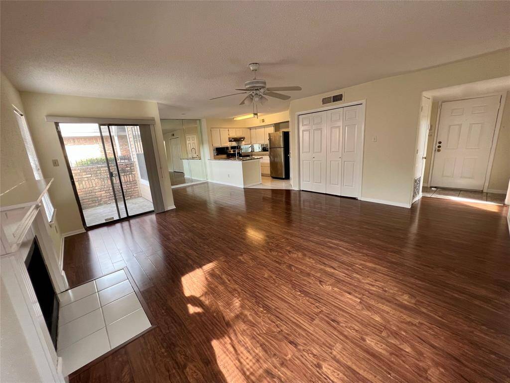 View from Living Room with ceiling fan, entry door on right, washer/dryer through double doors. Patio on left, adjacent to living room.