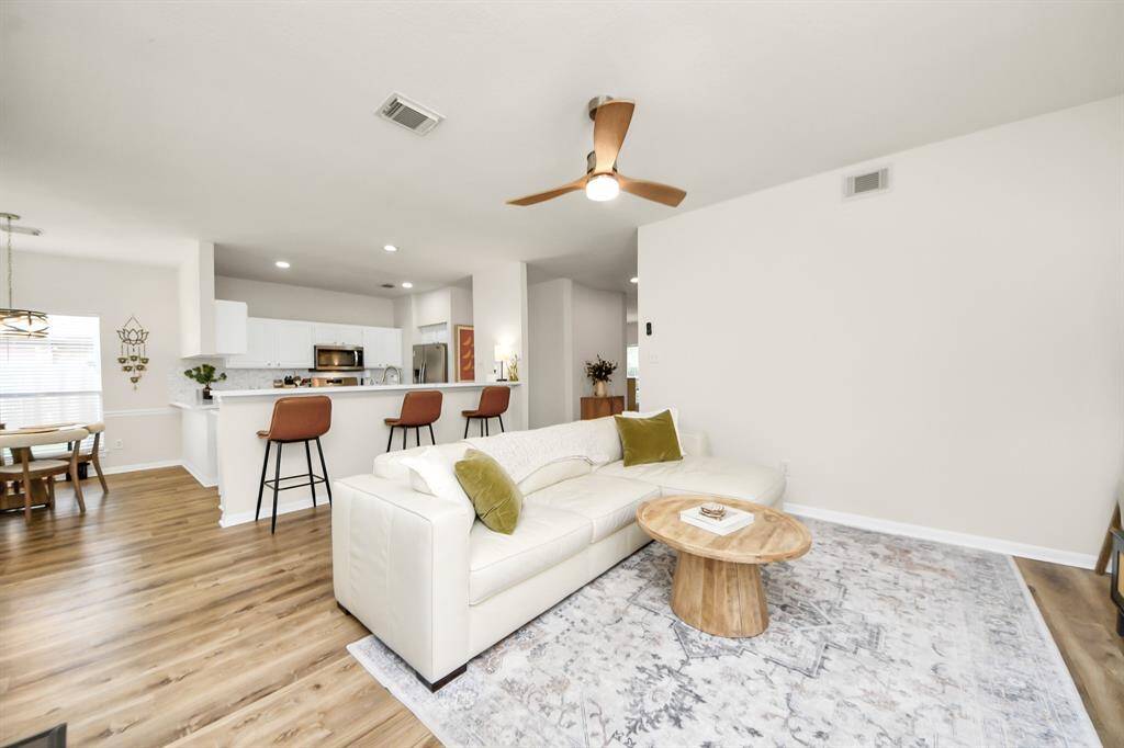 This photo showcase the living room, kitchen, and breakfast area, highlighting the bright, open-concept design and seamless flow between spaces.