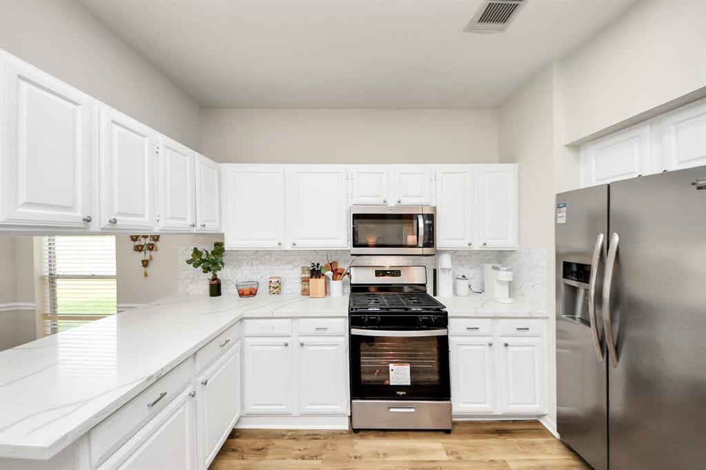 This bright, open kitchen features abundant cabinet storage and generous quartz countertops, providing plenty of room for cooking and gathering. With its open layout, it flows seamlessly into the adjacent living spaces—never feeling closed off, but inviting and connected.