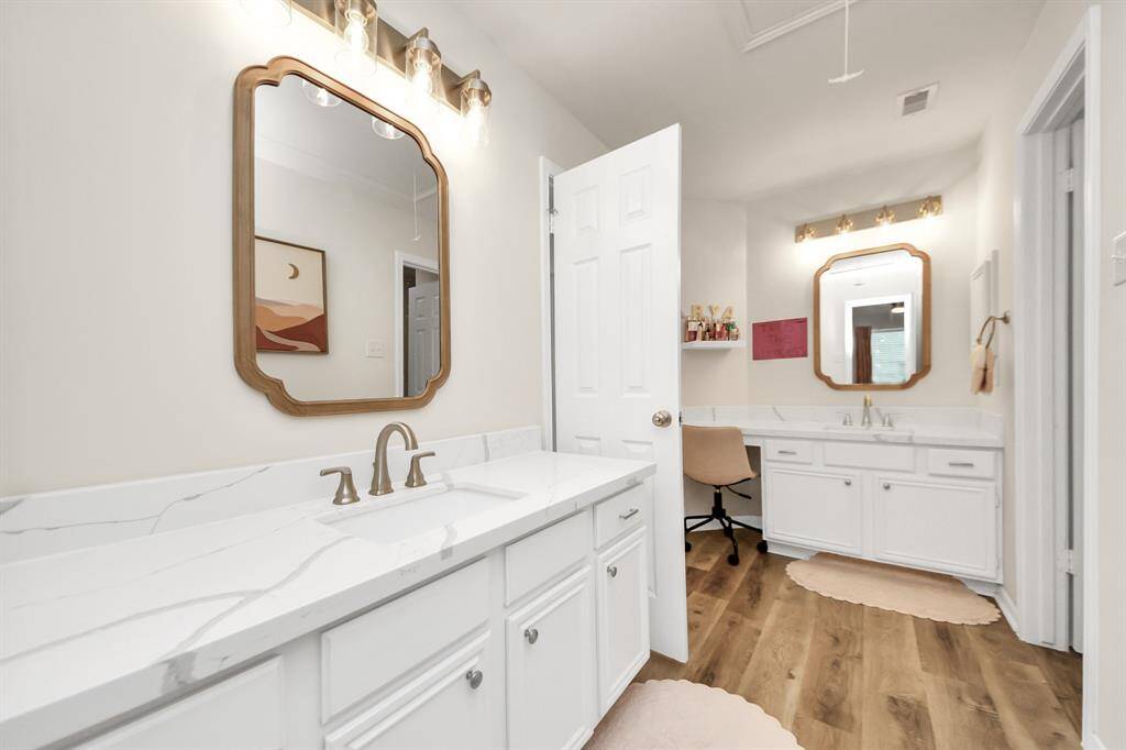 This well-designed bathroom connects directly to one bedroom and also has a separate door for easy access from the other secondary bedrooms. With two sinks, plenty of counter space, crisp white cabinetry, and a private walk-in shower, it offers both convenience and functionality—perfect for a growing family.
