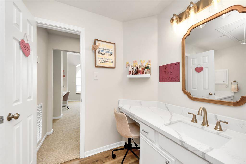 Another view of the spacious bathroom highlights the generous counter space and elegant faucet. You can also see the door leading to the flexible adjacent space, as well as the hallway connecting to the other secondary bedrooms.