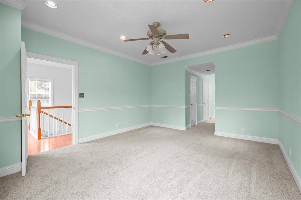 The primary suite features fresh carpet and paint, recessed lighting, elegant crown molding, and classic chair railing—creating a refined and comfortable retreat.