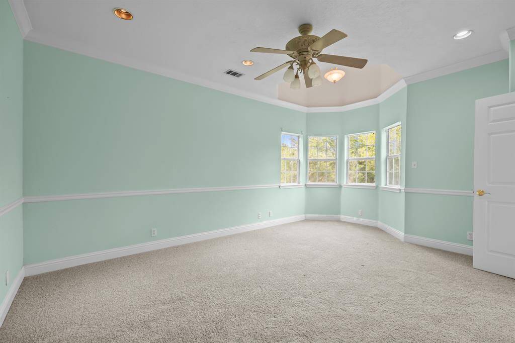 A cozy bay window seating nook is enhanced by a recessed tray ceiling, adding depth and architectural interest to the primary suite.