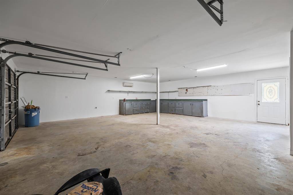 Stairs lead to the workshop garage, complete with built-in cabinets, a dedicated work area, and a convenient half bath. With ample space, it’s ready to become the dream workshop you’ve been envisioning.