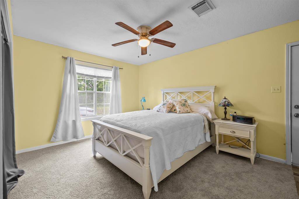 The guesthouse bedroom features a private back entrance, a bright window that fills the space with natural light, and fresh updates including new carpet and paint.