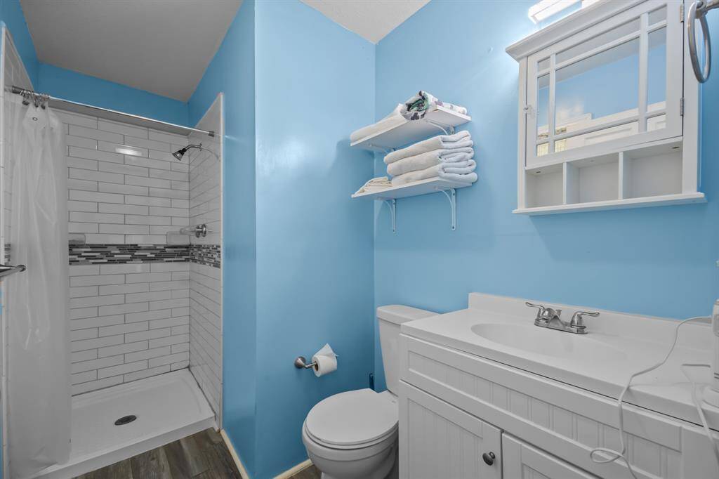 The updated bathroom features a fully tiled walk-in shower, granite countertop vanity, fresh paint, and new flooring—offering both style and comfort.