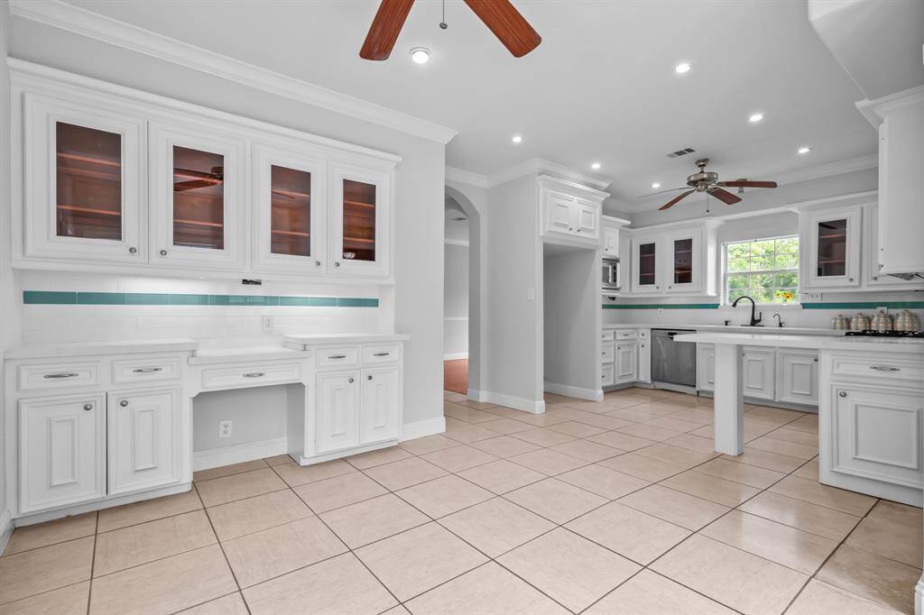 The updated kitchen showcases glass-front cabinets, granite countertops, ample storage, new fixtures, and a charming kitchen planning desk that adds both function and character.