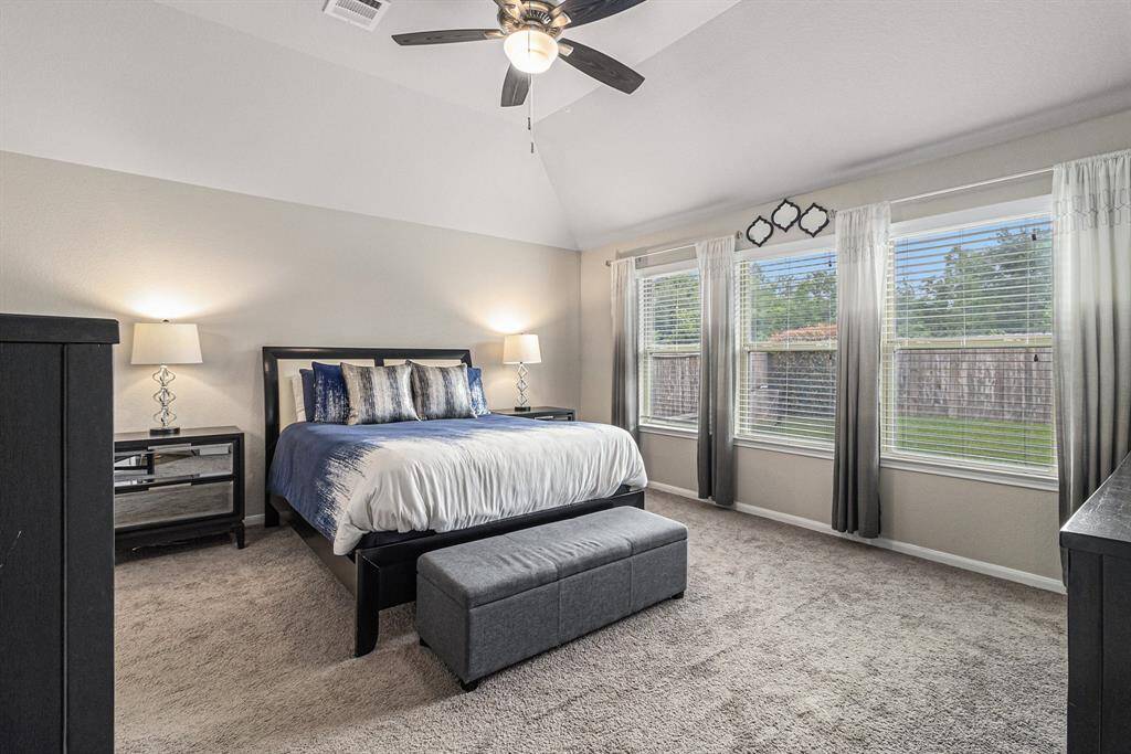 Lovely primary bedroom with high ceilings, windows overlooking your back yard, ceiling fan and cozy carpet.