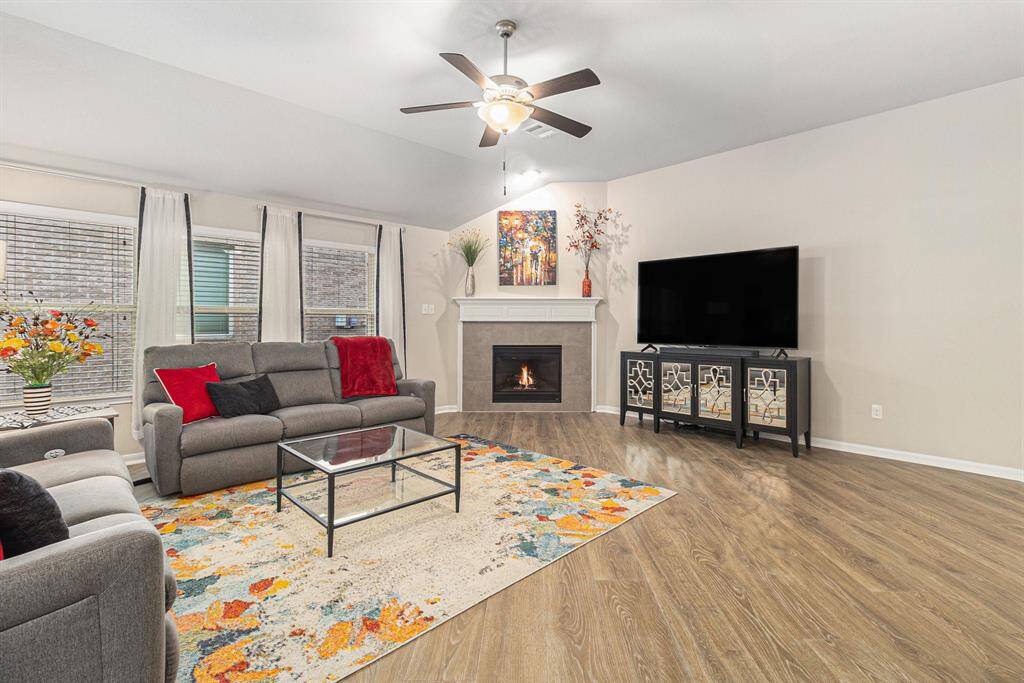 The living room features a cozy fireplace, modern ceiling fan, and large windows with plenty of natural light.