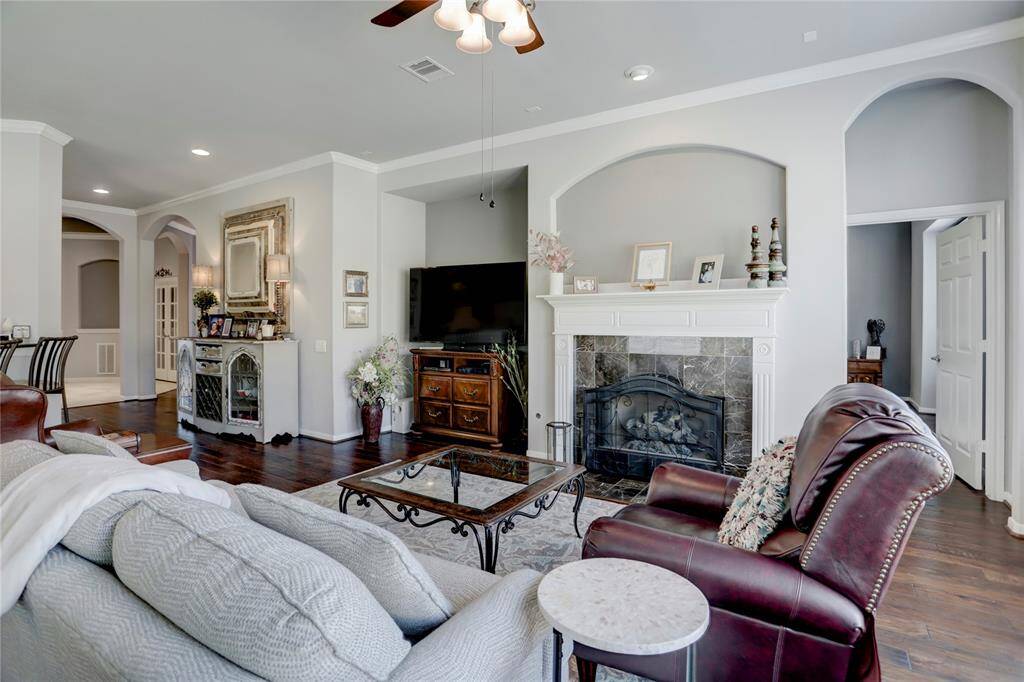This is a spacious and elegantly appointed living room with hardwood floors, a cozy fireplace, arched doorways, and high ceilings.