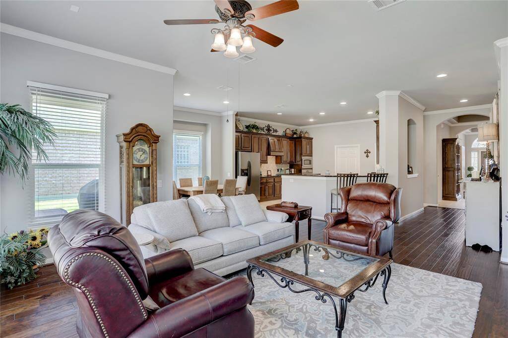 This is a spacious and well-lit living room with an open-plan layout that flows into the kitchen area. Large windows allow for plenty of natural light.