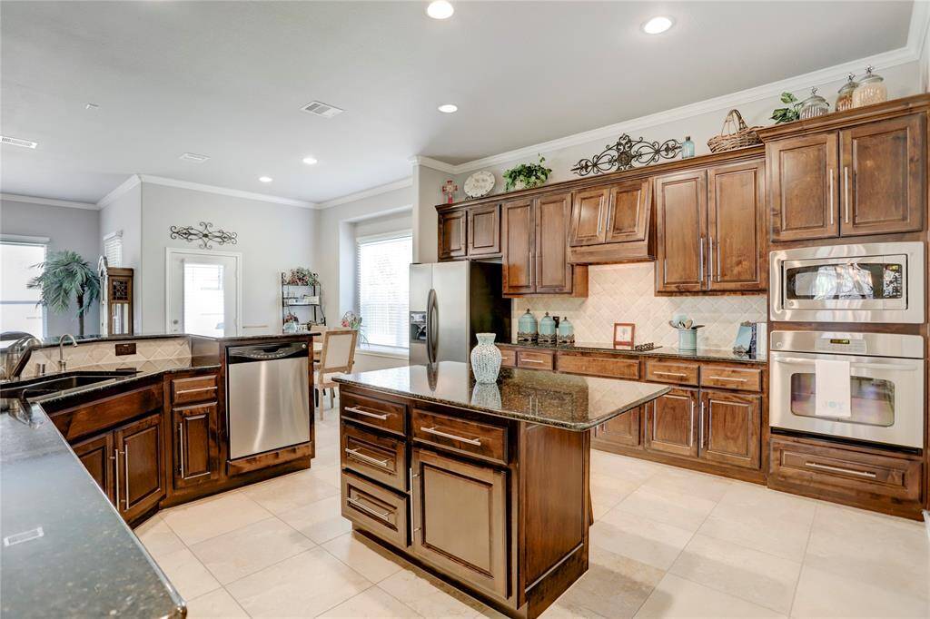 This kitchen features rich wooden cabinetry, granite countertops, stainless steel appliances, and a central island.