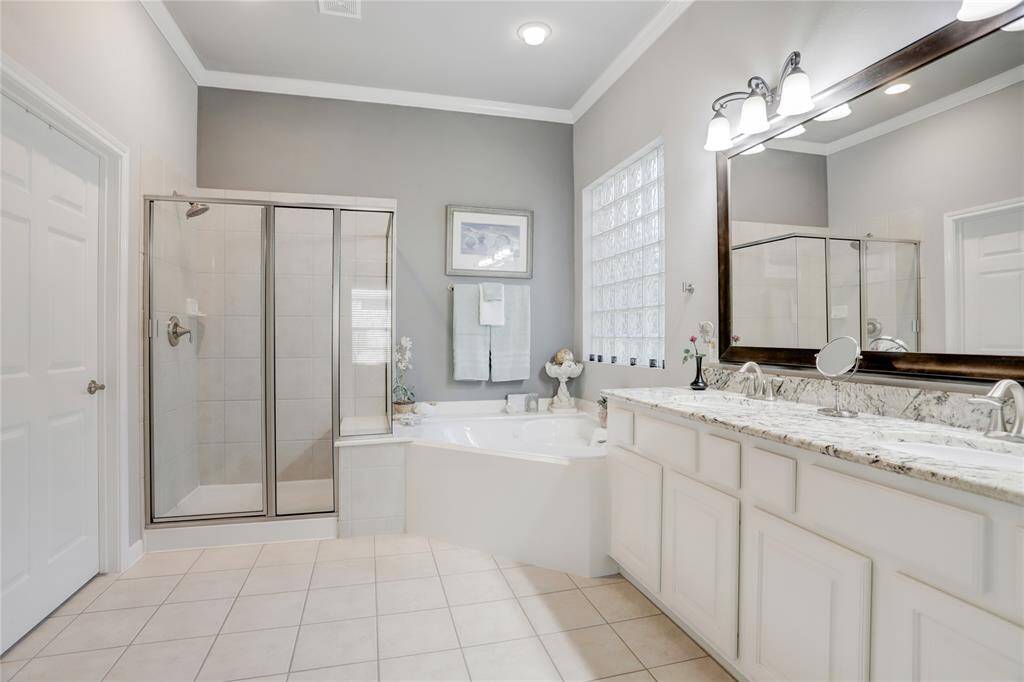 The primary bathroom boasts a large dual-sink vanity with granite countertop, a glass-enclosed shower with a built-in bench seat, and a separate jetted bathtub.