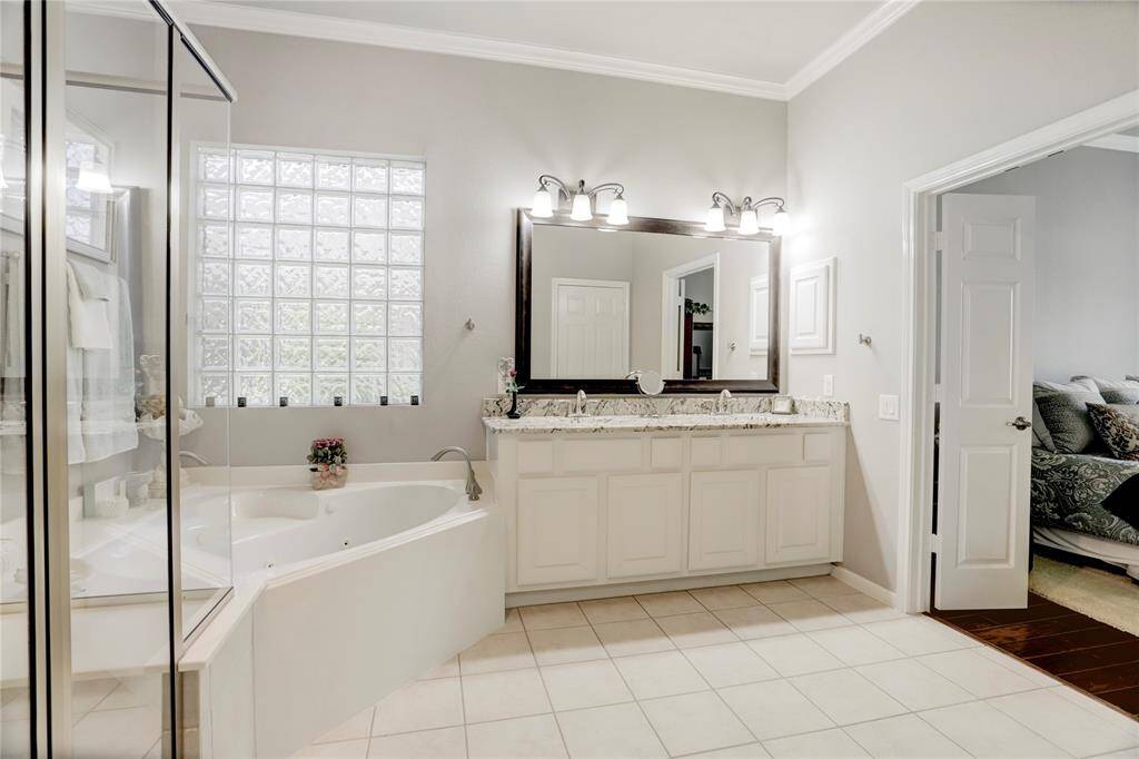This is a spacious and bright en-suite bathroom feature ample storage within the double vanity, linen shelves in the water closet and large closet.