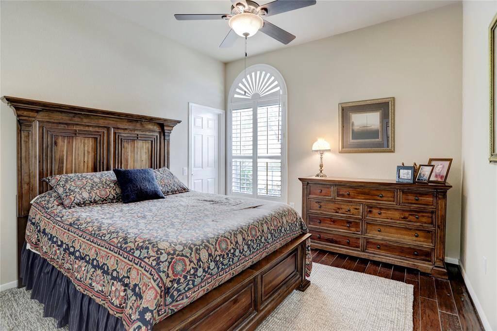 This front secondary bedroom is well-lit with engineered hardwood floors and an arched window with plantation shutters.