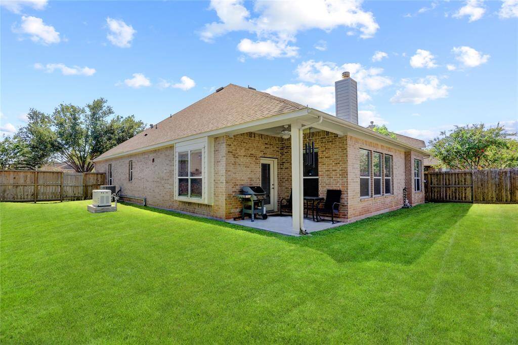 This is a single-story brick home featuring a well-maintained lawn, a covered patio area, and a privacy fence surrounding the backyard.