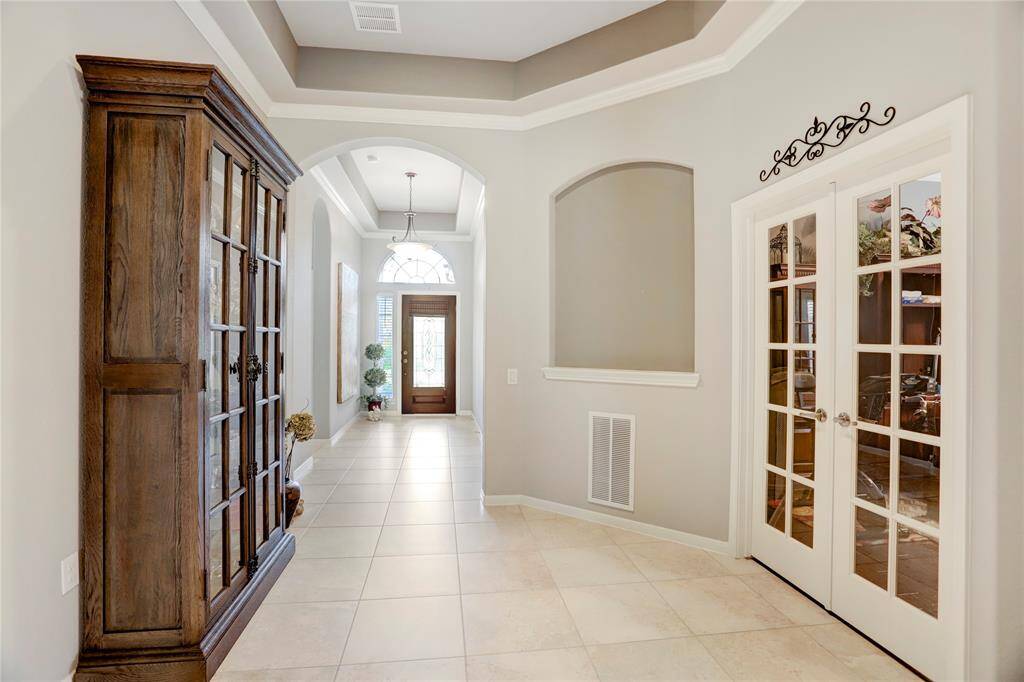 The foyer opens to a spacious, well-lit hallway, with French doors leading to the dedicated study.