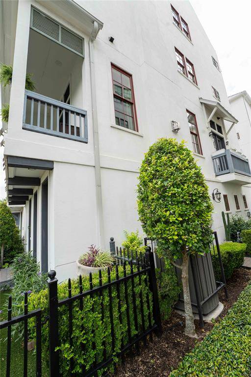 The home is surrounded by well-maintained greenery and a black wrought iron fence, contributing to its inviting curb appeal.
