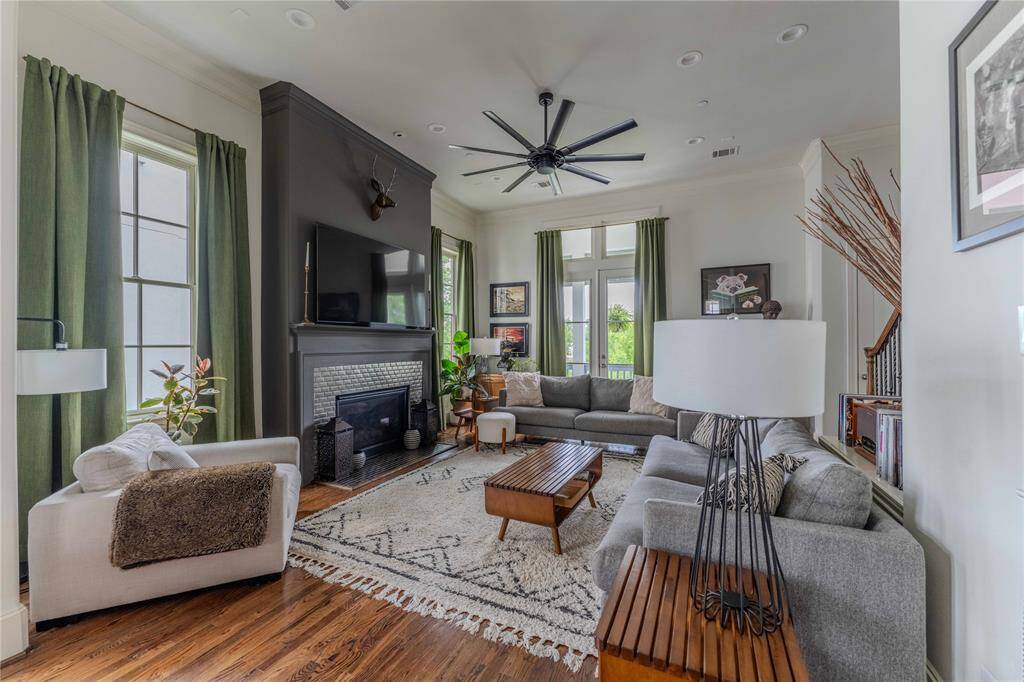 Flowing from the dining space, the room features gorgeous hardwood flooring, a sizeable ceiling fan, crown molding, recess lighting, substantial baseboards, and transome windows for extra natural light.