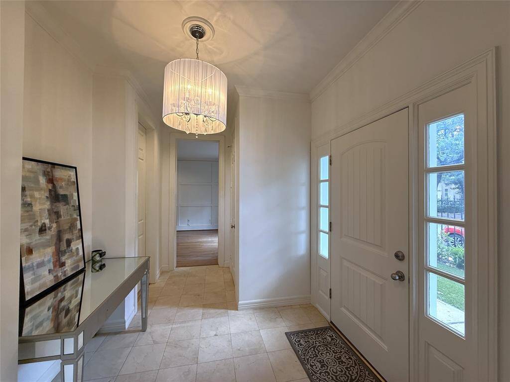Natural light flows into the entry foyer from windows on either side of the door. On the right and immediately by the door is a coat closet. On the left is the door into the garage. Notice the classy light fixture.