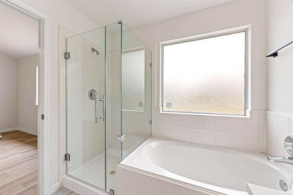 This additional view of the primary bath showcases a walk-in shower with tile surround and a separate garden tub perfect for soaking after a long day.