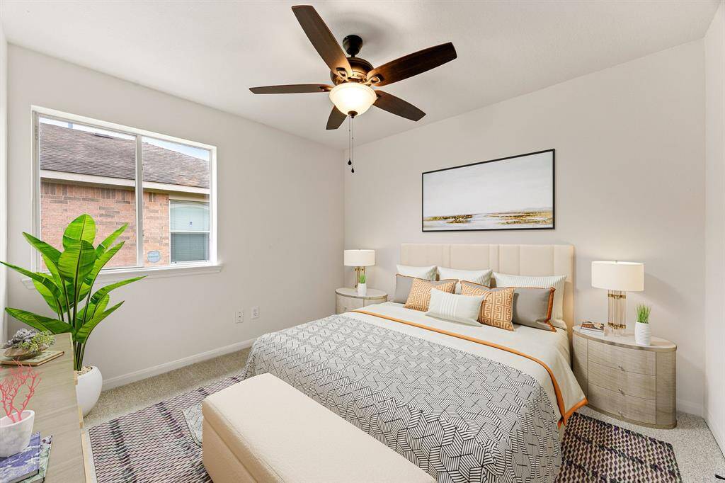 Secondary bedroom features plush carpet, neutral paint, dark stained ceiling fan with lighting and a large window with privacy blinds.