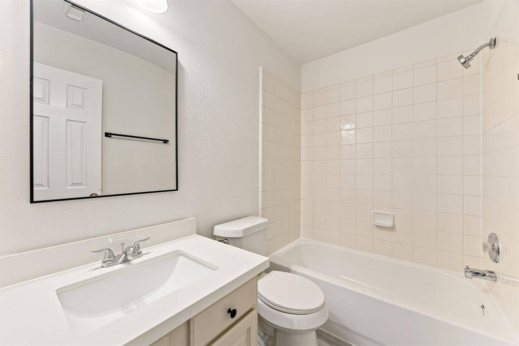 Secondary bathroom features light countertops and cabinets, neutral paint, shower/tub combo with tile surround, tile floors, sleek fixtures and modern finishes with plenty of space to accommodate any visiting family or guests