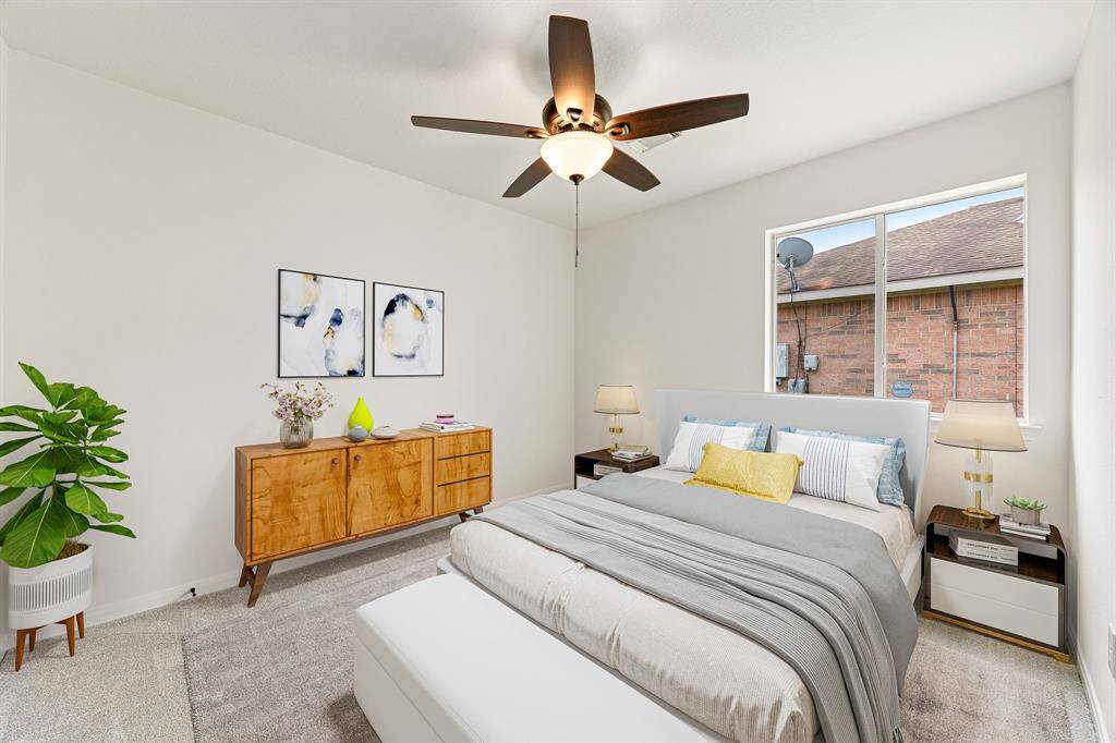 Secondary bedroom features plush carpet, neutral paint, dark stained ceiling fan with lighting and a large window with privacy blinds.