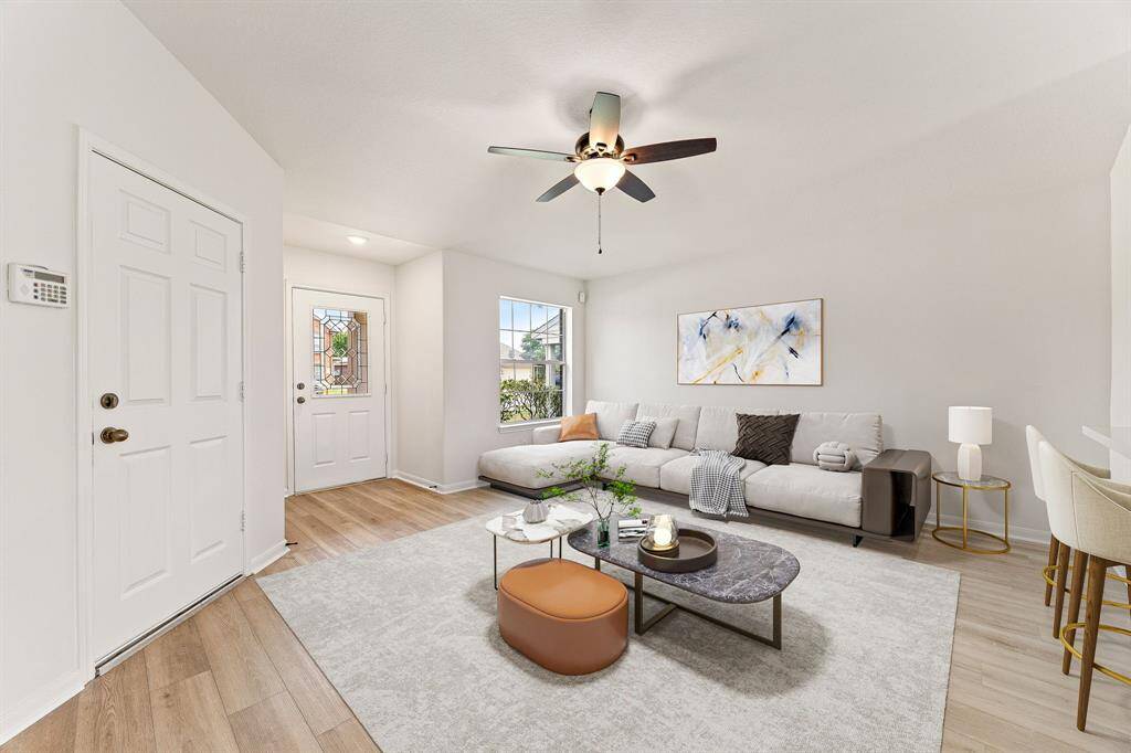 This living room is more like a GREAT room featuring neutral paint, dark stained ceiling fan, and a large window providing a lovely view of your front yard to keep an eye out on the kids or pets playing.