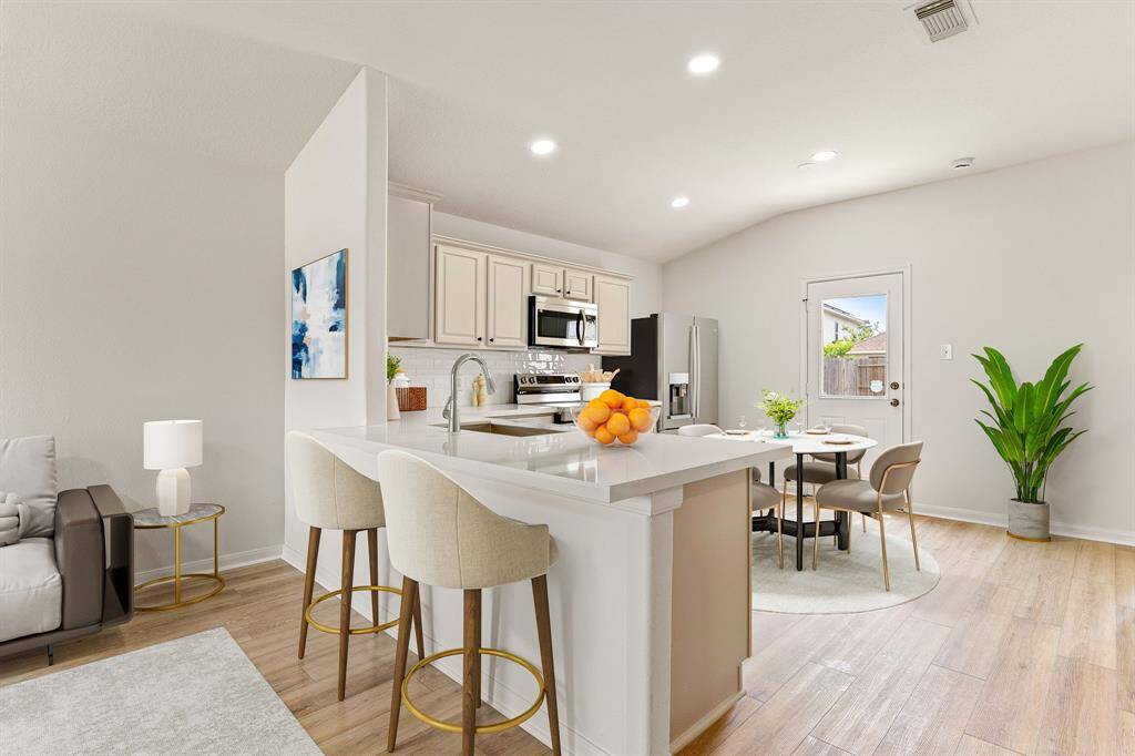 This stunning kitchen displays such a beautiful contrast with cream cabinets, neutral paint, quartz countertops, light modern backsplash, and SS appliances, breakfast bar with extra storage, recessed lighting and high ceilings.