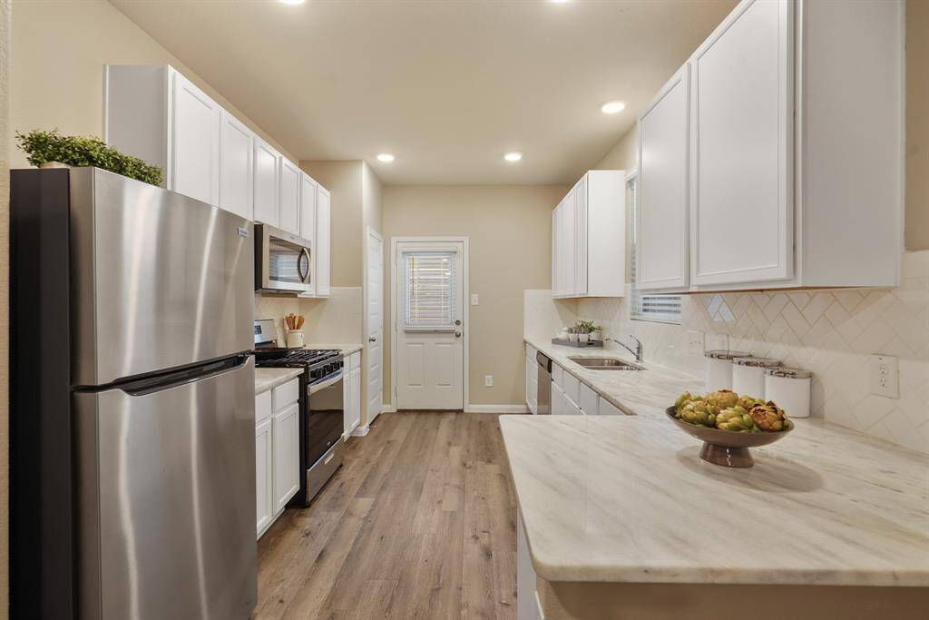 This fully loaded kitchen offers sleek granite countertops, crisp white cabinetry, Herringbone/Subway tile backsplash, and modern stainless steel appliances; refrigerator included! The spacious layout provides ample workspace for both meal prep and cleanup, making it as functional as it is stylish.
