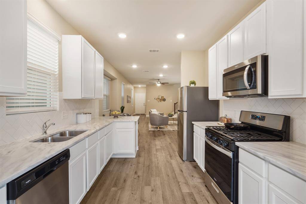 Ditch the takeout and enjoy home-cooked meals in this stylish kitchen with granite countertops, crisp white cabinetry, subway tile backsplash, and stainless steel appliances—including the refrigerator. The spacious design offers plenty of room to prep, cook, and gather.