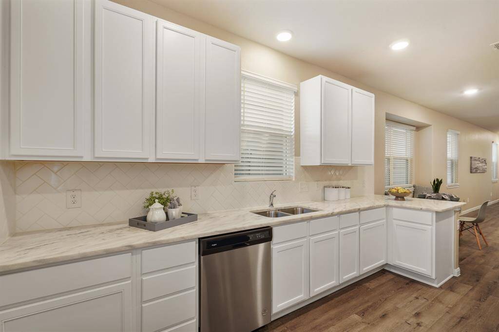 Bright and beautiful, this kitchen showcases granite countertops, herringbone-pattern backsplash, and abundant cabinetry plus a large pantry. There’s plenty of space to store your favorite kitchen gadgets and keep everything organized with ease.