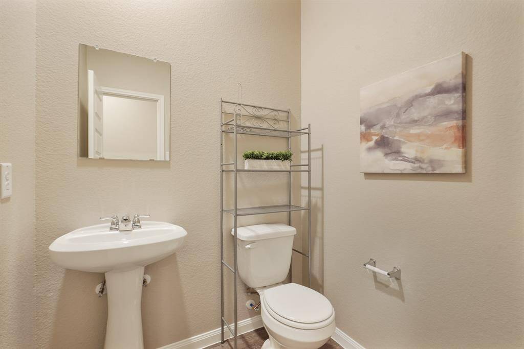 The first-floor powder bath is convenient for guests offering LVP flooring, neutral paint, and a classic pedestal sink.