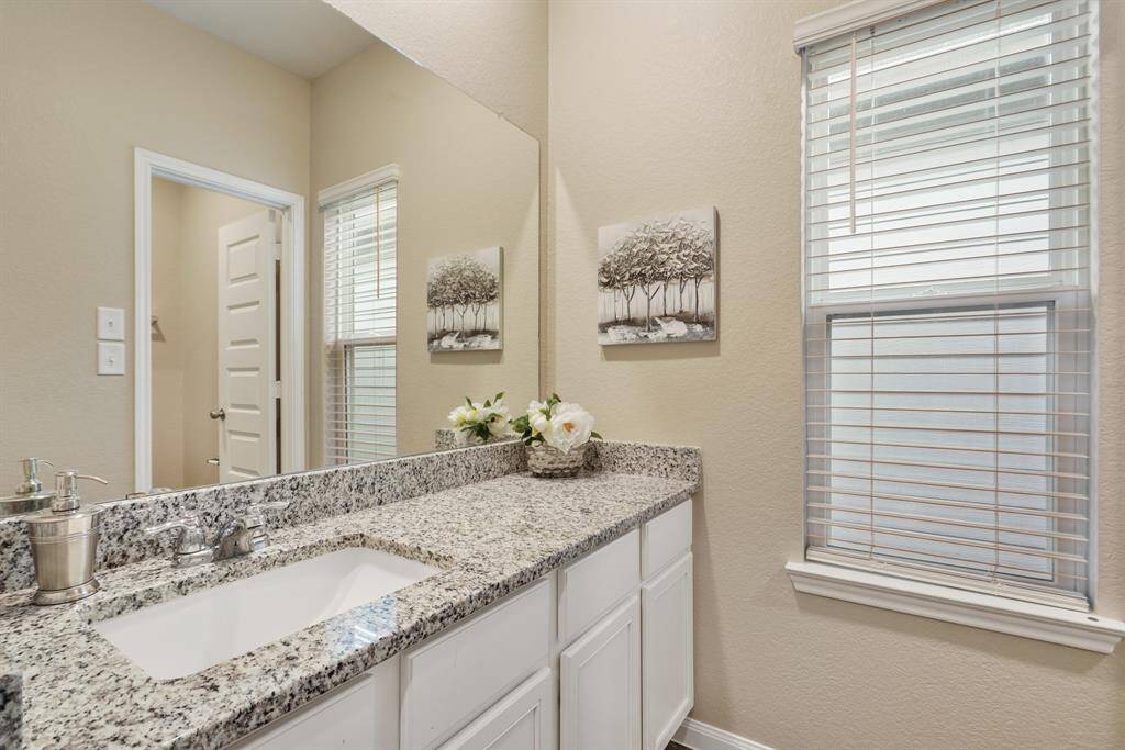 The guest bathroom upstairs offers an extended granite-topped single sink vanity, complete with a full-width mirror above and ample storage below. It’s a stylish and functional space perfect for busy mornings and daily routines.