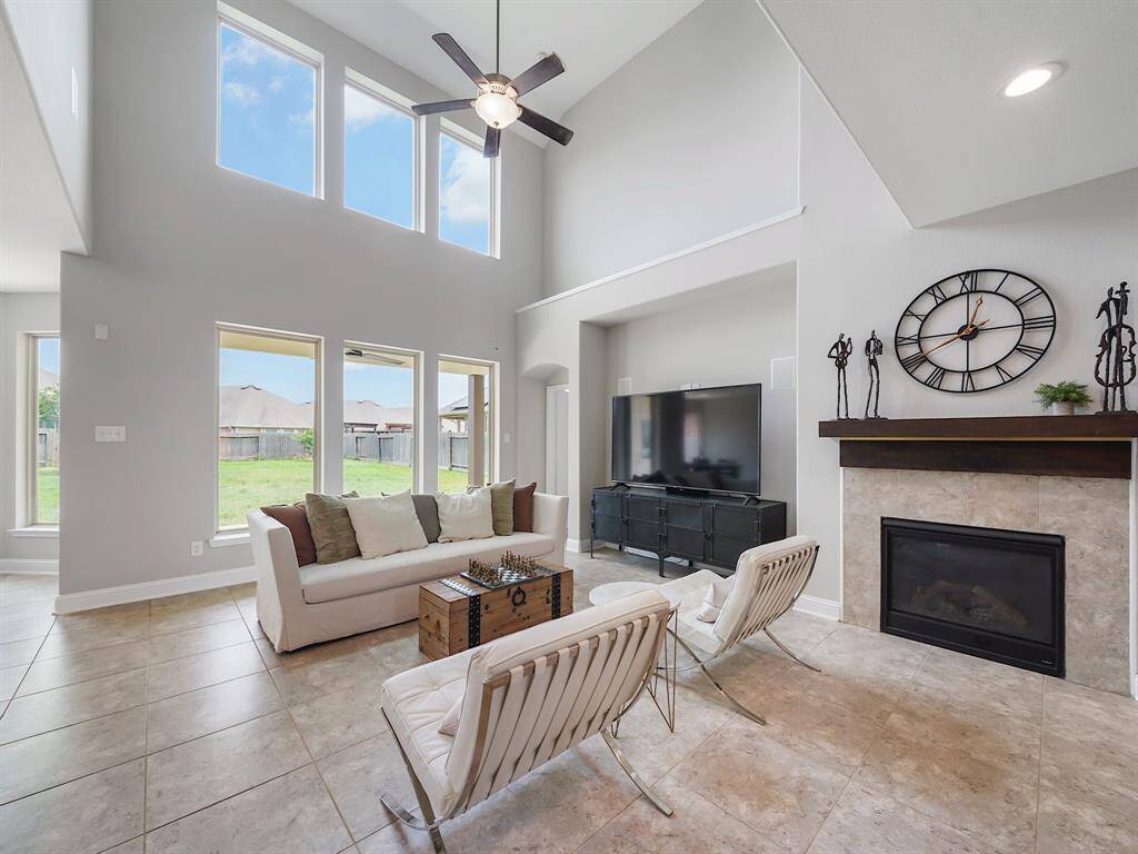 The two-story living room features soaring floor-to-ceiling windows, creating a dramatic and airy atmosphere. A thoughtfully designed wall inset offers seamless integration for your entertainment system, complemented by a striking fireplace that adds warmth and sophistication.