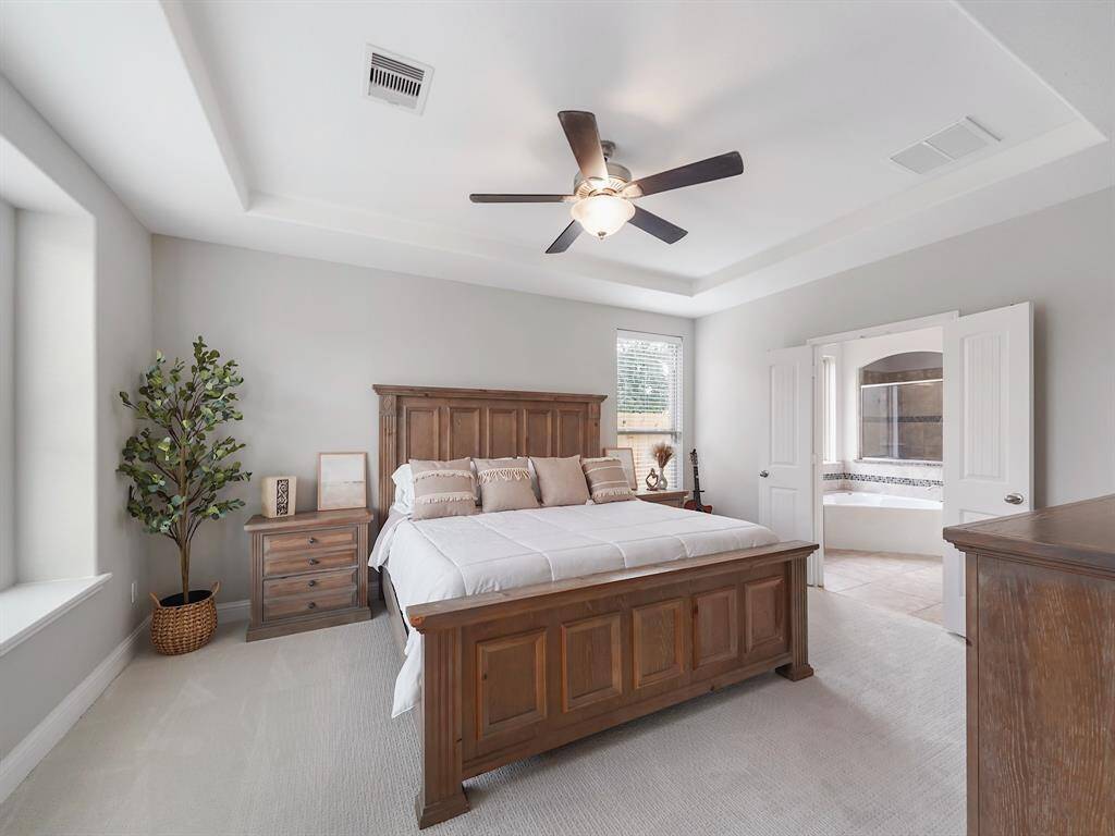 The primary bedroom is a true haven, boasting a sophisticated tray ceiling that adds dimension and character. Elegant French doors lead to the private ensuite bathroom, providing a convenient and luxurious space to prepare for the day or unwind after a long one.