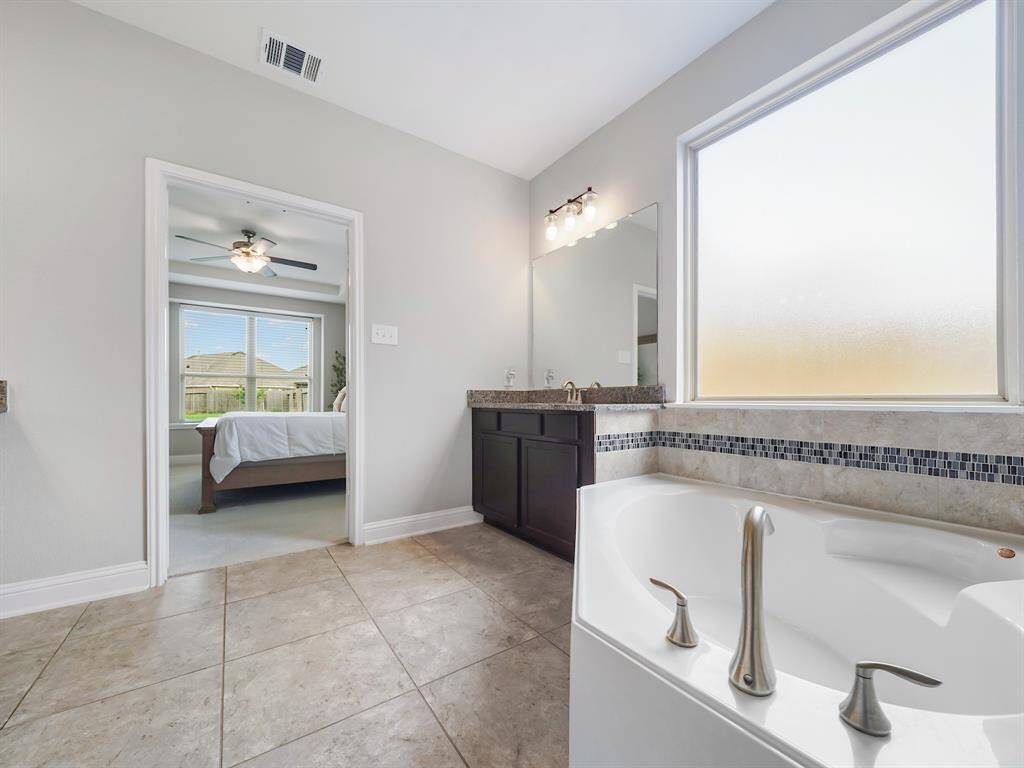 Indulge in tranquility with a spa-like bathroom featuring a deep soaking tub. A frosted window above provides ample natural light while ensuring privacy, creating the perfect atmosphere for relaxation.