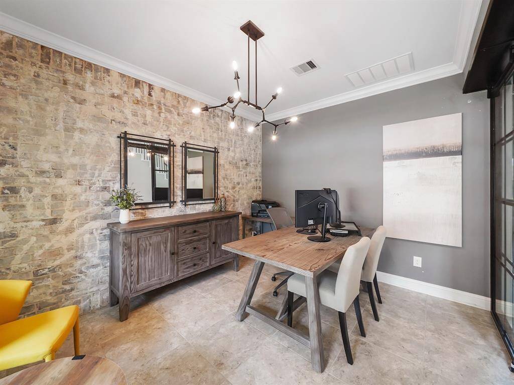 Boasting sophisticated crown molding, a striking brick accent wall, and a contemporary light fixture, this is the perfect environment to cultivate creativity and productivity.