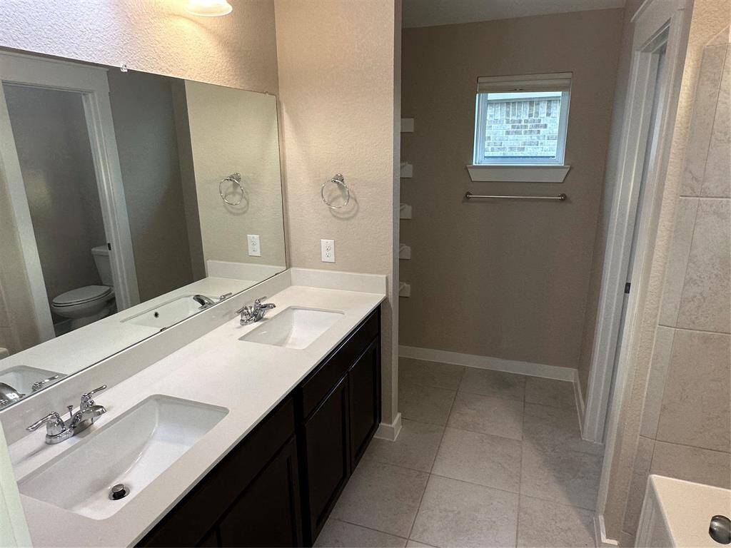 Primary bath with dual sinks, private water closet, storage area.