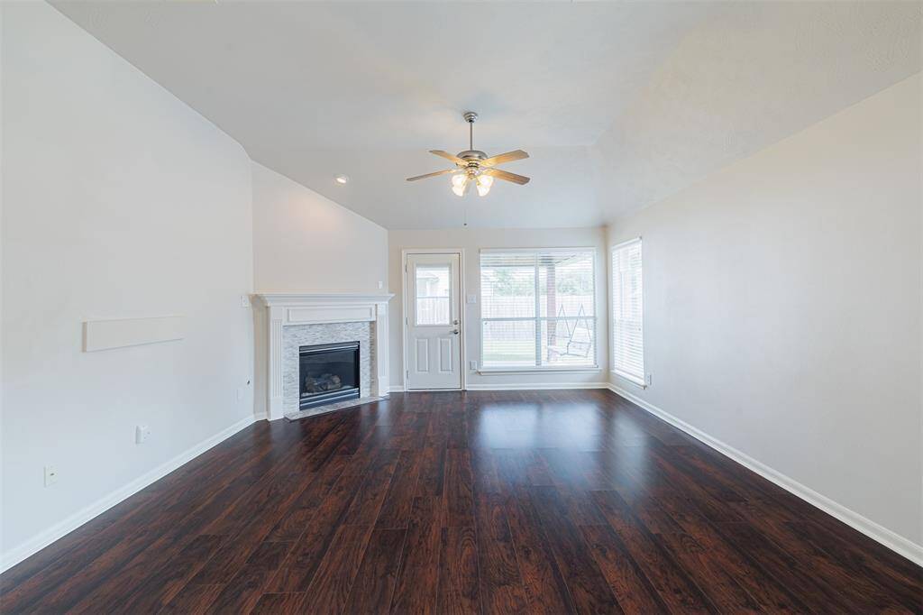 The open-concept family room includes soaring ceilings, a gas log fireplace, and backyard views.
